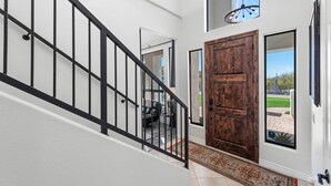 A staircase with a black railing leading to a room with a wooden door and a view of the outdoors. - 1+ Acre 5 Bedroom Desert Oasis with Pool and Mountain Views! (Apache Junction)