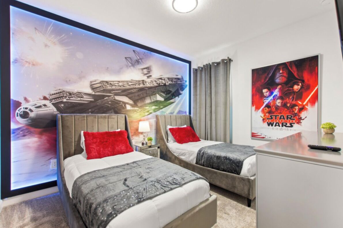 A hotel room with two beds, a Star Wars poster, and a large ship image on the wall.
