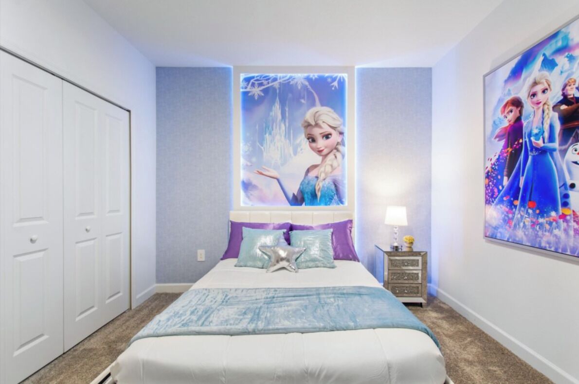 Une chambre à coucher avec un lit, une table de chevet, une commode et deux affiches accrochées aux murs.