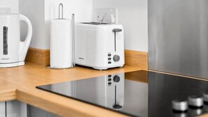 Een keuken met een witte koffiezetapparaat, een keukenrolhouder en een broodrooster op een houten aanrecht.