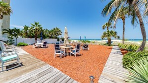 Una terrazza fronte spiaggia con posti a sedere all'aperto, palme e vista sull'oceano.