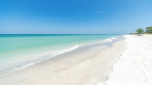 Een strand met helder turquoise water en wit zand.