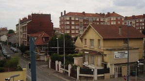 Eine Wohnstraße mit Häusern, einer Fußgängerampel und einem Schild, das eine Bushaltestelle anzeigt.