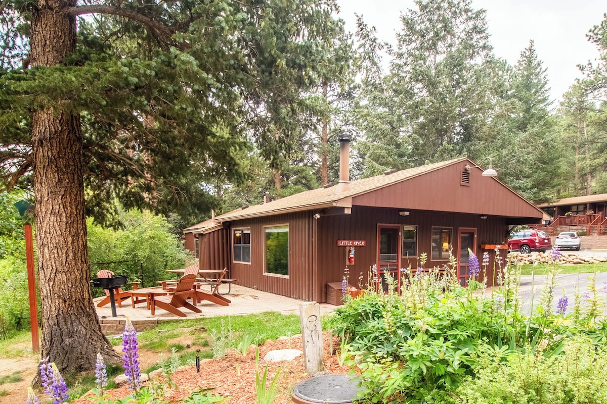 A lodge with a large tree in front, outdoor seating, and a sign reading "Little River".