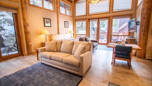 A cozy living room with a sofa, a dining table with chairs, and a fireplace. - Castle Mountain Lodge (Estes Park)