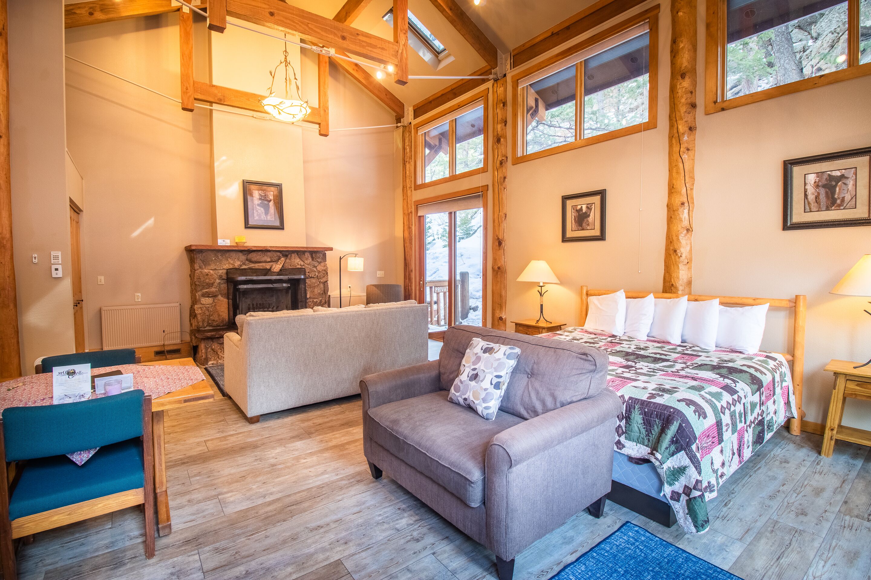 A cozy room with a fireplace, a bed with a quilt, a sofa, and a dining table with chairs.
