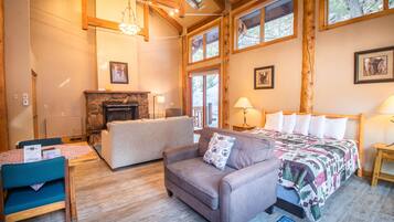 A cozy room with a fireplace, a bed with a quilt, a sofa, and a dining table with chairs.