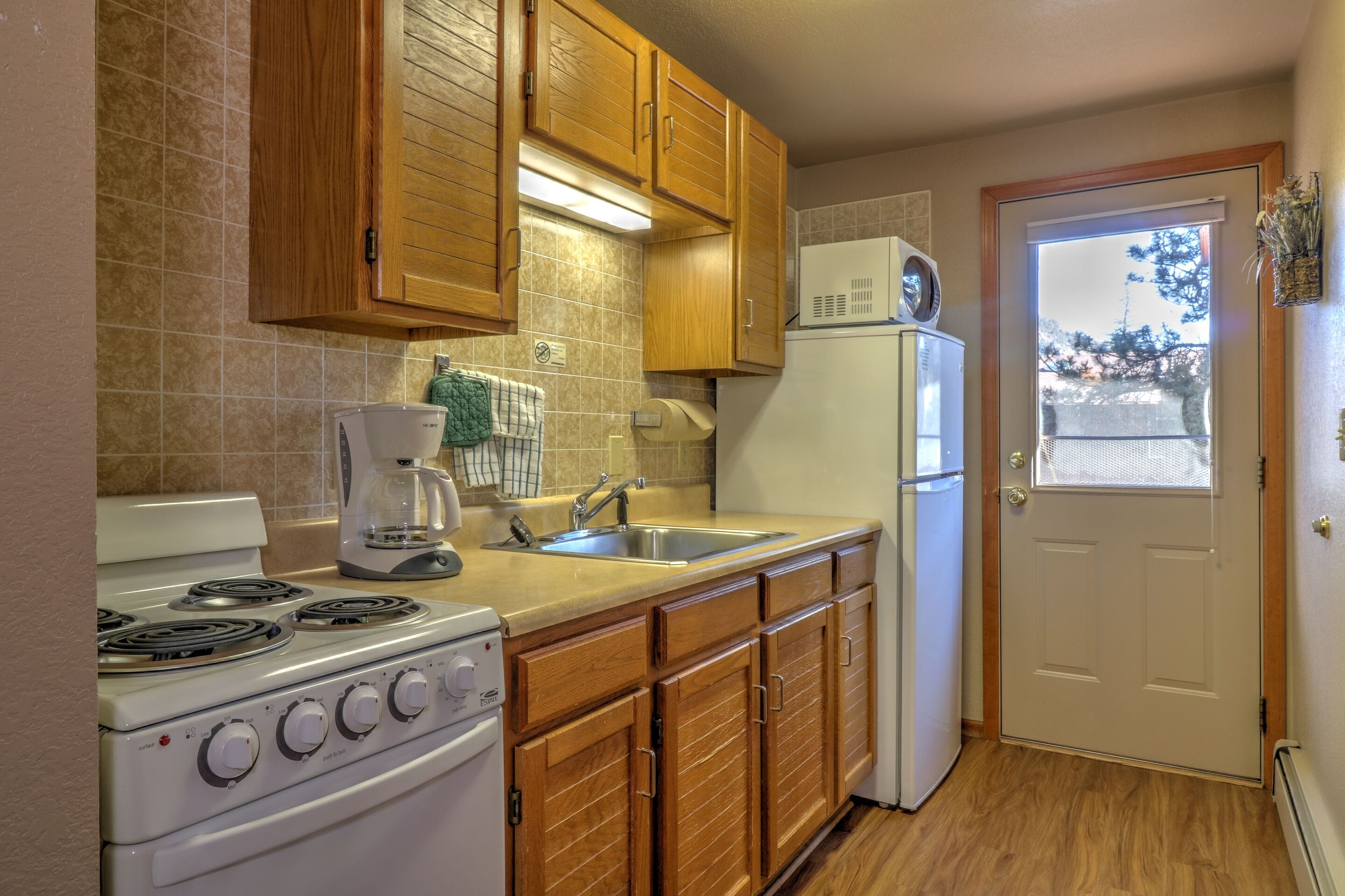 A kitchen with wooden cabinets, a stove, a sink, and a refrigerator.