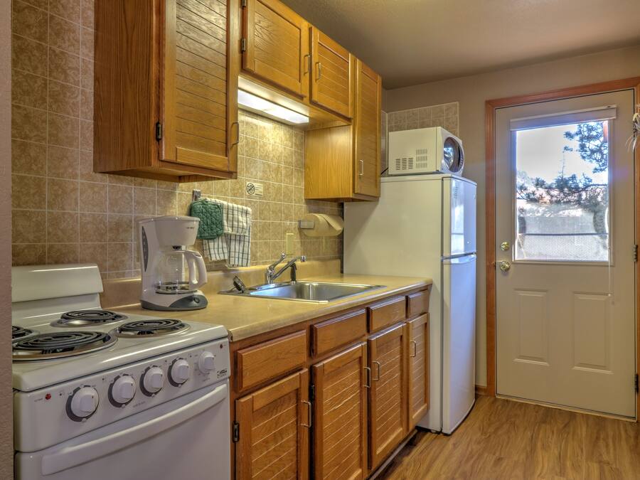 A kitchen with wooden cabinets, a stove, a sink, and a refrigerator.