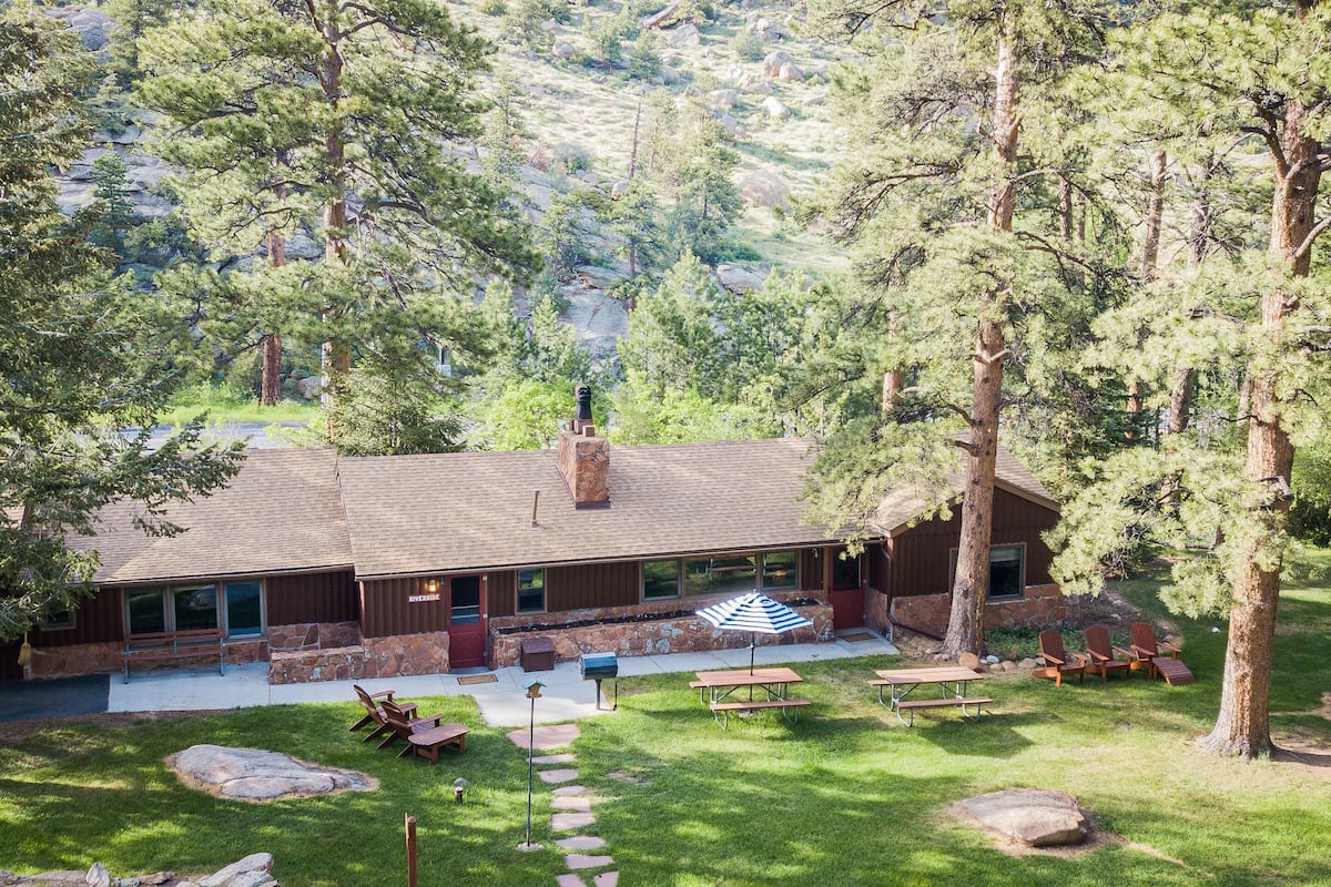 A lodge with a stone facade, large windows, and a patio area with outdoor seating and picnic tables.