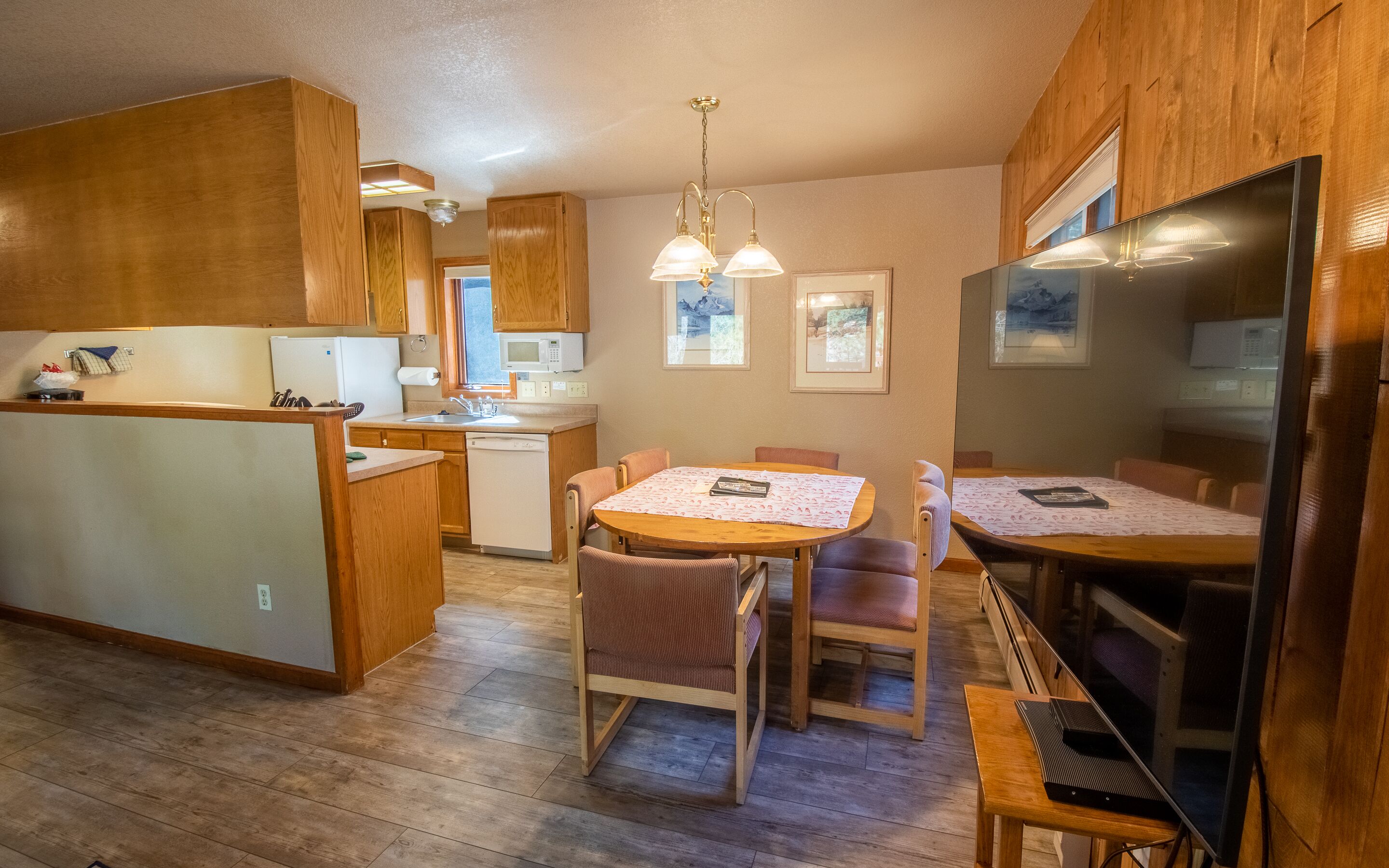 Una cocina compacta con armarios de madera, una isla central y un comedor con mesa y sillas.