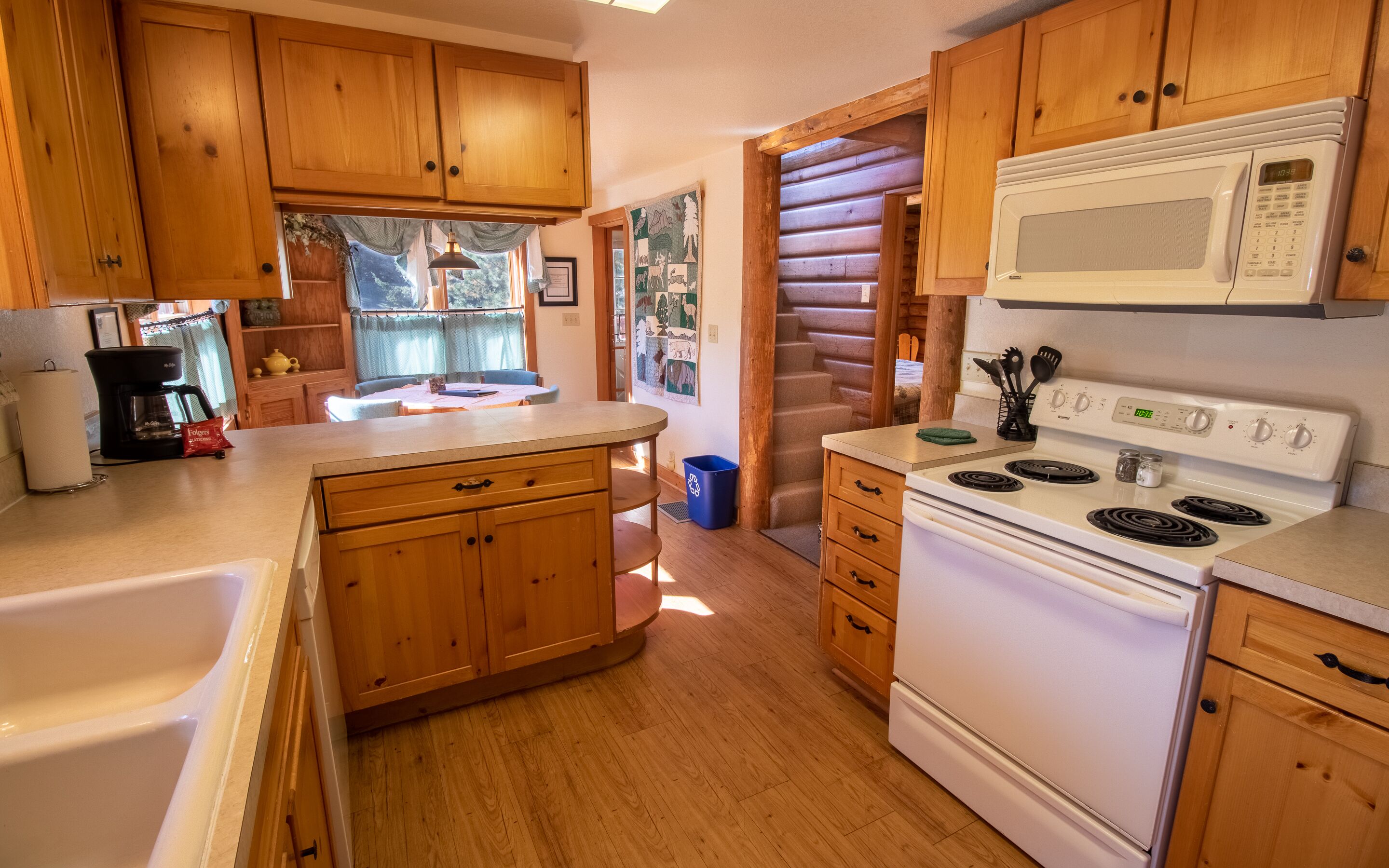 Une cuisine avec des meubles en bois, une cuisinière blanche et une machine à café.