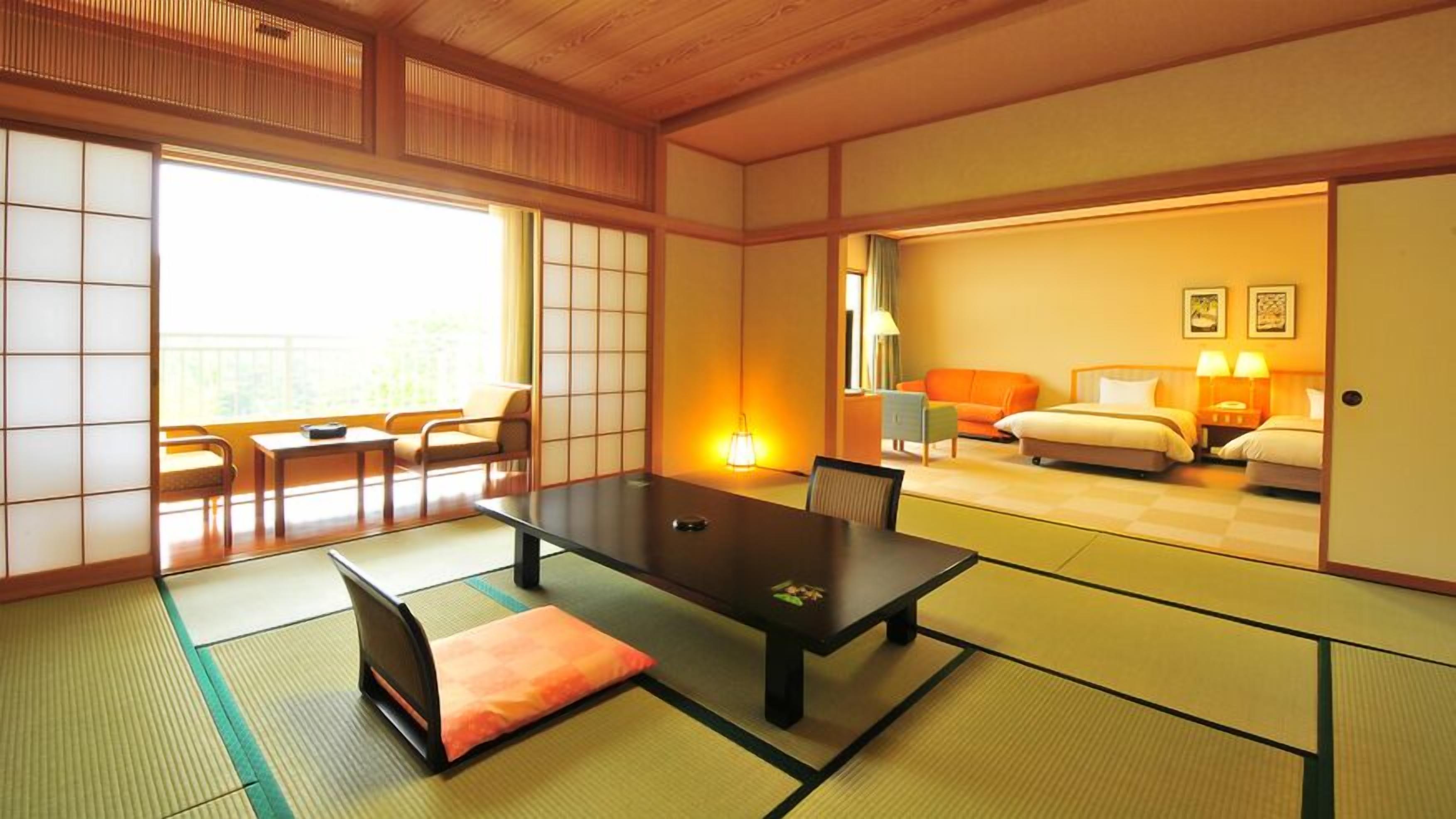 A traditional Japanese-style room with tatami flooring, a low table, a sofa, and a bed.