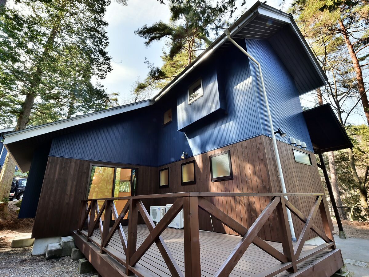 A two-story wooden cabin with a deck and a small attached structure.