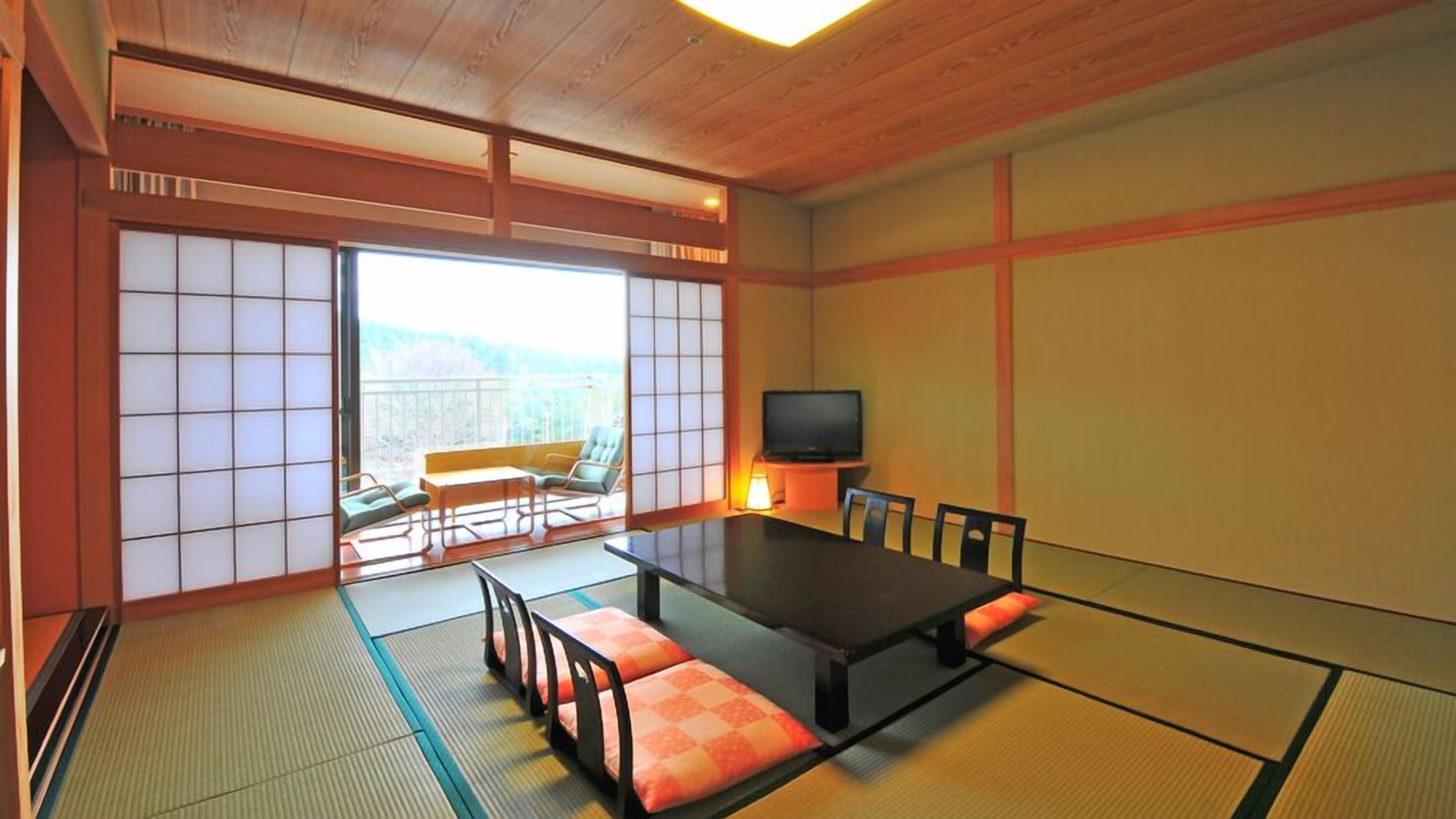 A traditional Japanese room with tatami flooring, a low table, chairs, a television, and a sliding door leading to a balcony.