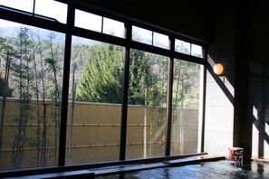A room with large windows, a bamboo fence, and a water feature.
