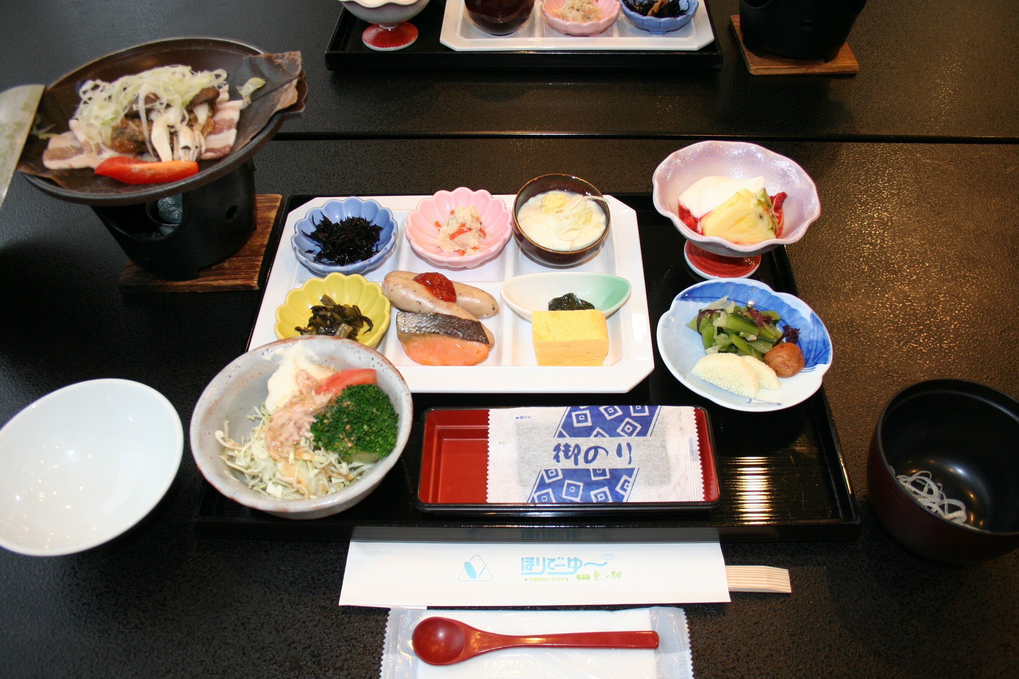 A variety of dishes on a tray, including sushi, vegetables, and possibly some meat.