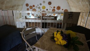 A dining area with a table set for two, a chair, and a decorative wall with sun motifs. - Yellow gecko--in the heart of the stones (Matera)