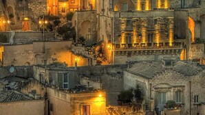 A densely packed urban area with historic stone buildings, some with arched doorways and windows, and warm ambient lighting. - Yellow gecko--in the heart of the stones (Matera)