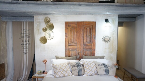 A bedroom with a wooden wardrobe, a bedside table with a lamp, and decorative pillows. - Yellow gecko--in the heart of the stones (Matera)