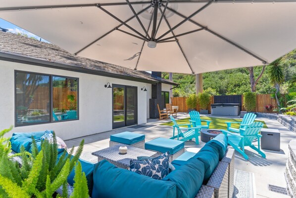 A patio with outdoor furniture, a large umbrella, and a fire pit. - Poppy Cottage Home 4BR (Carlsbad)