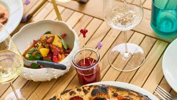 Zwei Pizzen auf einem Holztisch, während Wein in ein Glas gegossen wird.