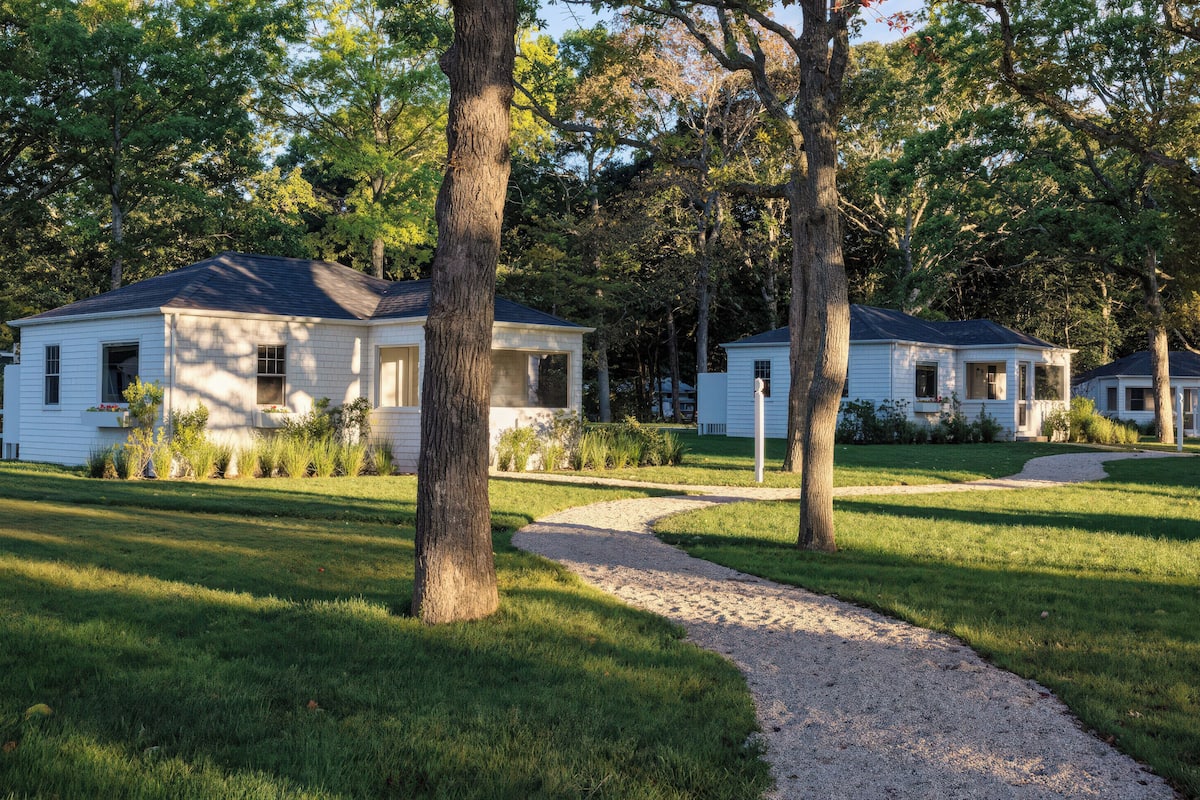 A row of white single-story houses with a gravel driveway and a grassy lawn.