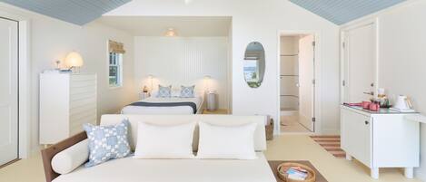 A bedroom with a bed, a sofa, a desk, and a mirror.