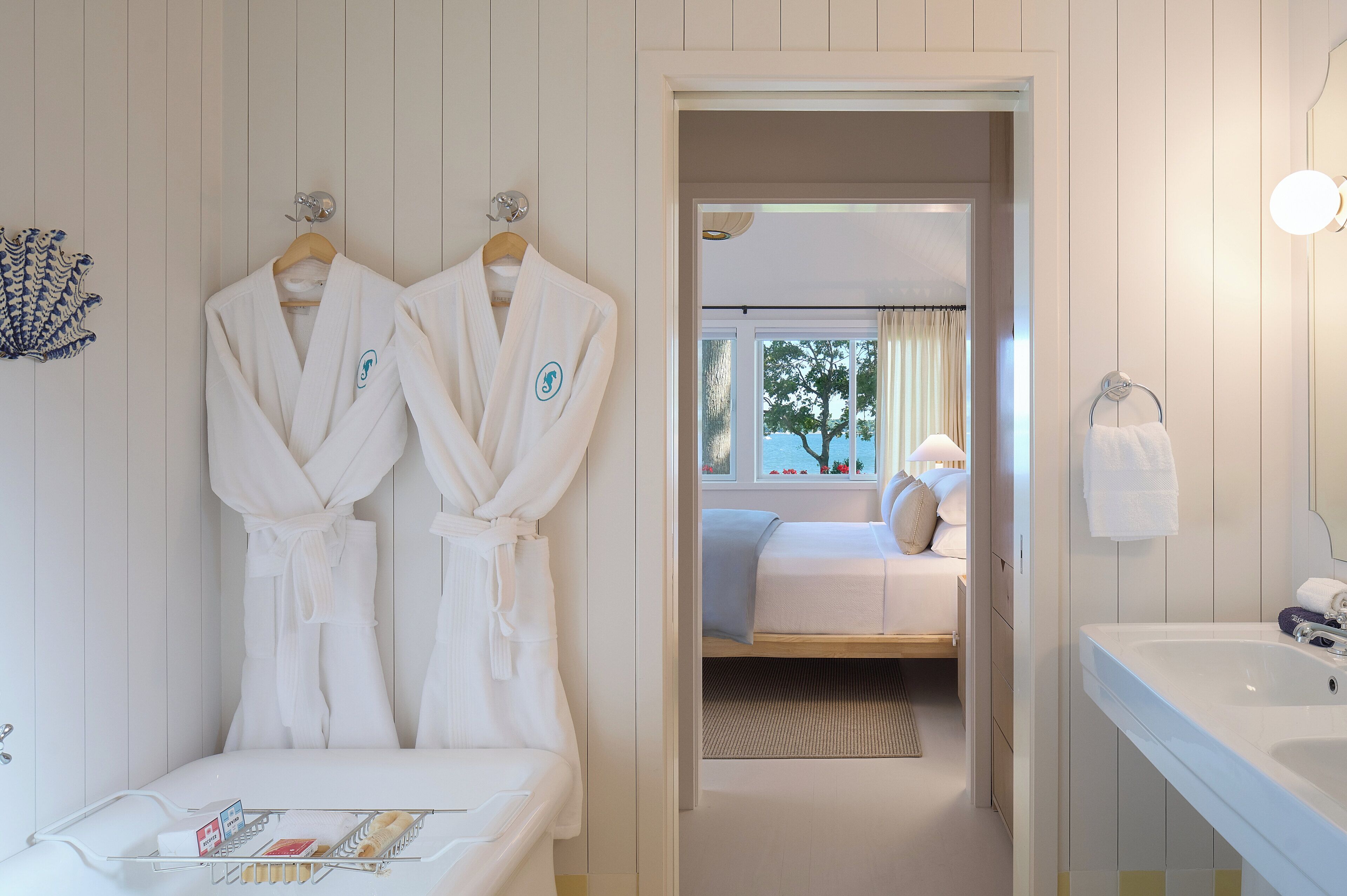 Una habitación de hotel con una cama, una mesita de noche, un espejo y una ventana con cortinas.