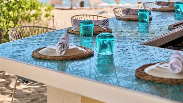 A seaside dining area with tables, chairs, and umbrellas, overlooking a body of water. - Silver Sands Motel & Beach Bungalows (Greenport)
