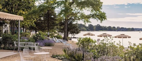 Outdoor seating with tables and chairs, a covered area, and a view of the water.