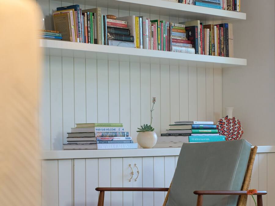 Ein Zimmer mit Bücherregal voller Bücher, einem Korbstuhl und einem kleinen Topfpflanzen.