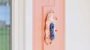 A wall-mounted lamp with a white shade, a decorative ceramic piece, and a door with a peach-colored panel.