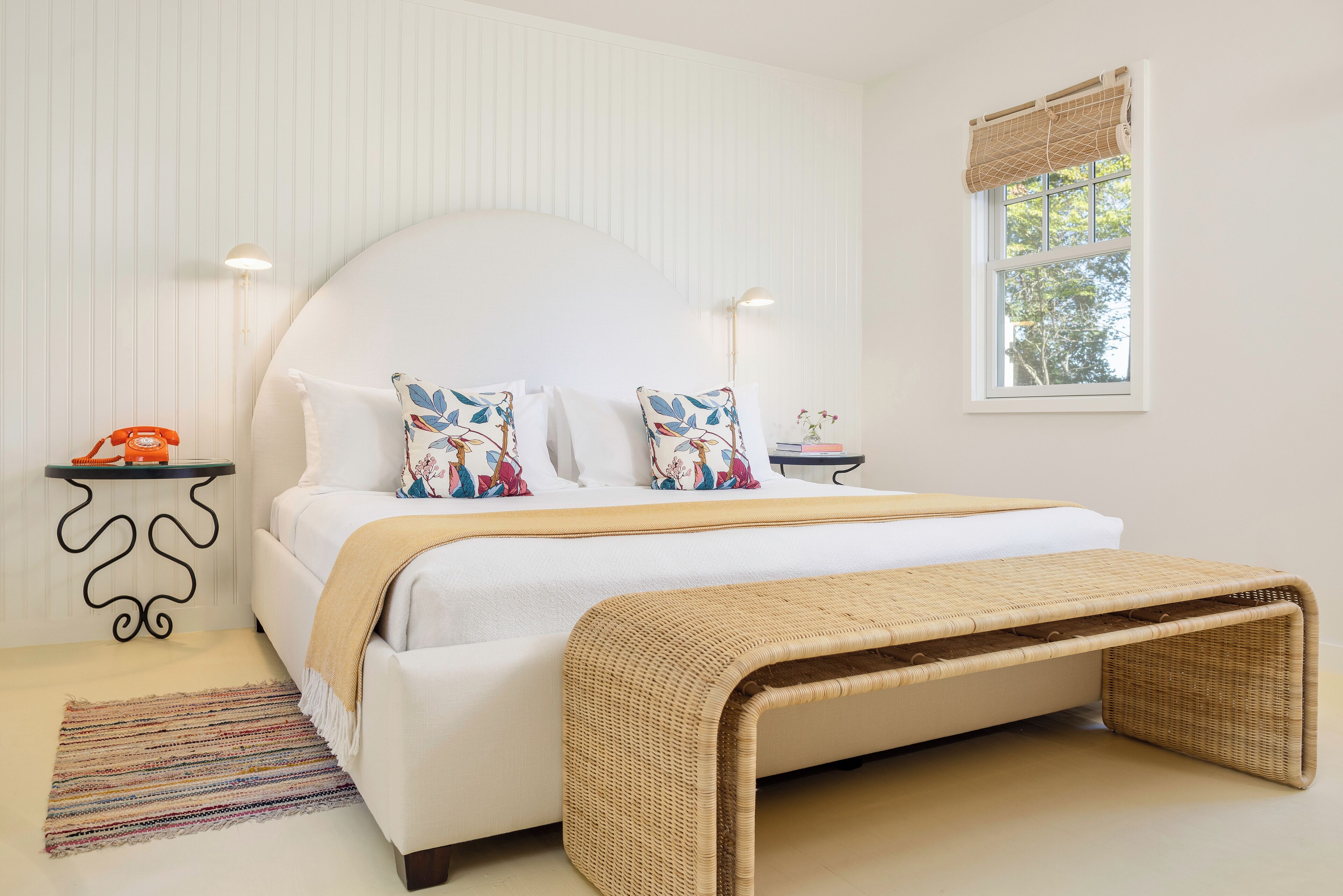 Ein Schlafzimmer mit Bett, Nachttischen, einem Fenster mit Blick und einer Wandlampe.