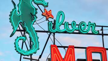 A neon sign with a seahorse and the word "Silver" on a rooftop.
