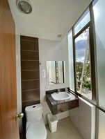 Un baño moderno con inodoro, lavamanos y un espejo grande.