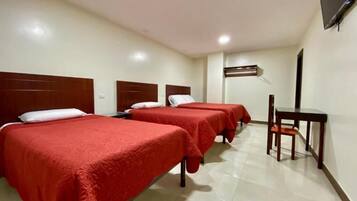 A hotel room with three beds, a desk, and a chair.