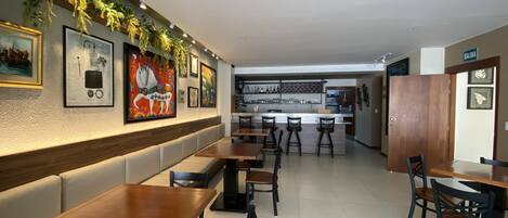 Un restaurante con una barra larga, mesas tipo cabina y una zona de bar.