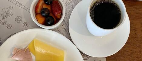 A breakfast plate with scrambled eggs, toast, ham, cheese, and a side of fruit.