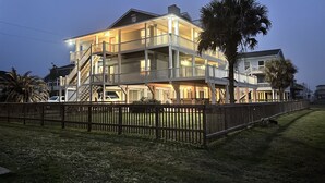 Una propiedad frente al mar de varios pisos con balcones, una escalera y una valla de madera.