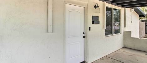 A white door with a doormat, a small window, and a wall-mounted light fixture.