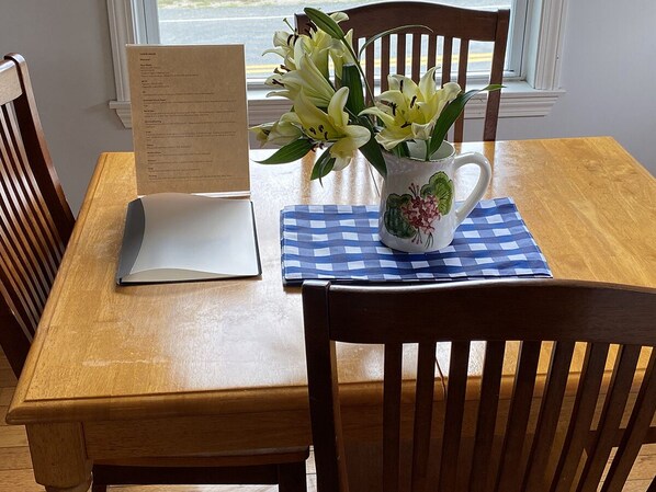 Ein Holztisch mit einem Laptop, einer Speisekarte und einer Vase mit Blumen.