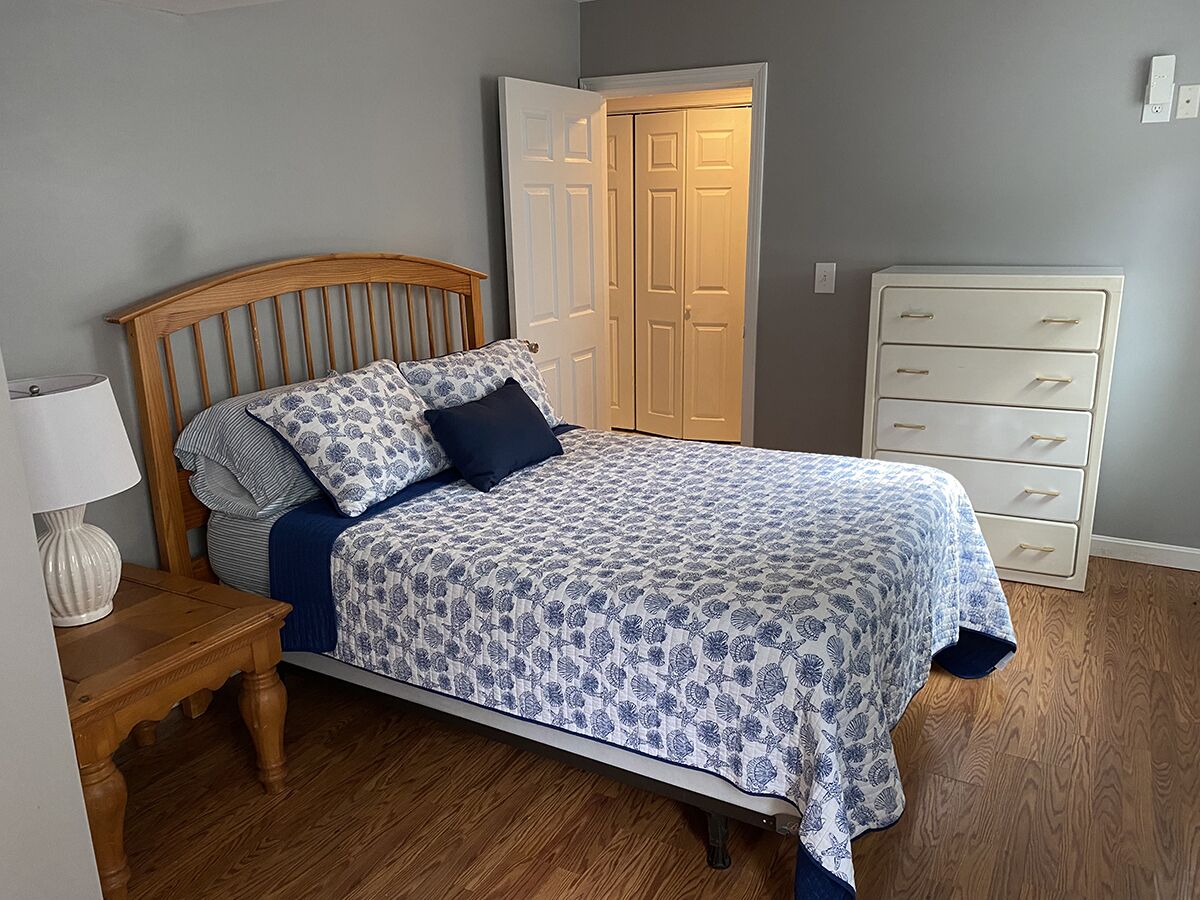 Une chambre à coucher avec un lit en bois, une table de chevet, une commode et une porte.