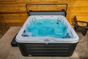 Un jacuzzi con un fondo de pared de madera, estructura metálica y suelo de hormigón.