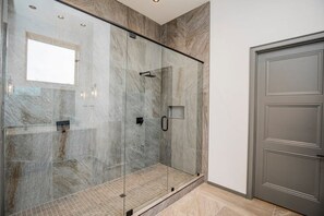 A modern bathroom with a glass-enclosed shower, marble walls, and a wooden floor. - Bike House 2 - HotTub - Direct MTB Trail access (Bentonville)