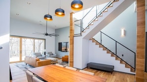 Un intérieur moderne avec une table à manger en bois, un escalier et une grande fenêtre.