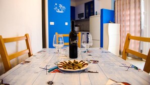 Un tavolo da pranzo con una bottiglia di vino, due bicchieri e un piatto di cibo.