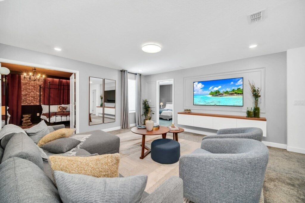 Ein modernes Wohnzimmer mit großem Flachbildfernseher, grauen Sofas, einem Couchtisch und einer Ziegelwand als Blickfang.