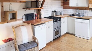 Cocina compacta con estufa, horno, microondas y armarios blancos.