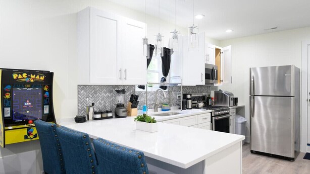 Una cocina moderna con armarios blancos, electrodomésticos de acero inoxidable y una isla central.